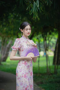 花裙少女持紫扇立于竹林前