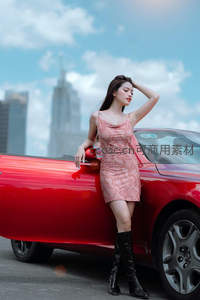 红裙美女倚靠敞篷车城市天际线