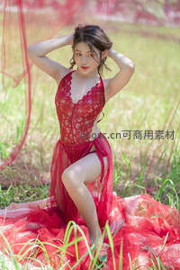 红裙少女草地上双手撩发展露自信笑容