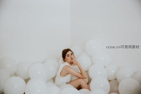 白色气球海洋中的沉思少女