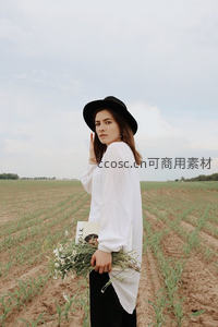 田野间戴帽女子手捧雏菊