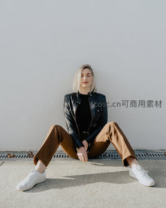 简约白墙前盘腿而坐的时尚女性