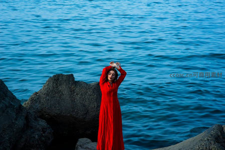 红裙女子立于海边礁石之上