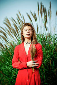 红衣女子怀抱芦苇闭目享受