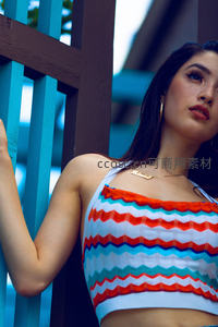 彩条泳衣美女倚靠蓝色栅栏