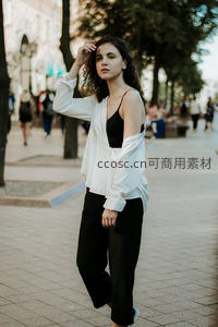 卷发女孩街头漫步，白衬衫黑裤显随性