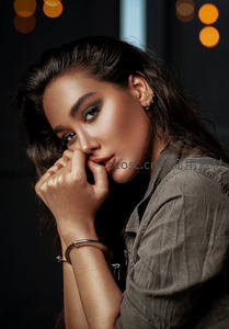 暗调光影下，精致妆容女子托腮凝视