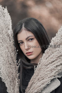 深色长发女子倚靠芦苇丛温柔凝望