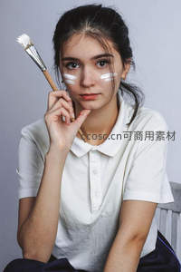 少女持画笔面颊抹白颜料