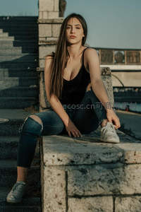 阳光下石阶上的慵懒街头女孩