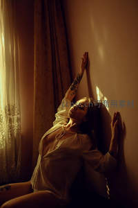 暖光窗边慵懒女子，纹身与光影交织柔美