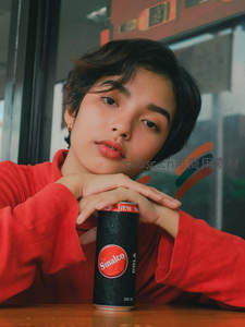 红衣少女托腮凝视可乐罐