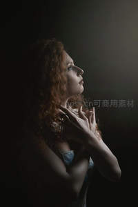 侧颜祈祷的红发女子在暗影中