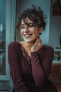 卷发女子窗边微笑，温暖惬意时光