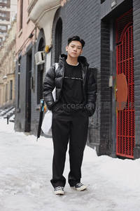 街头雪地青年穿羽绒服站立