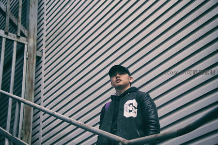 街头青年倚靠栏杆，工业风背景显酷感