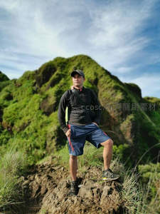 山巅徒步者凝视远方，绿意盎然背景