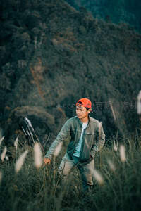 山野草丛中戴橙帽青年徒步探索