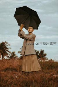 田野中男子撑黑伞仰望天空