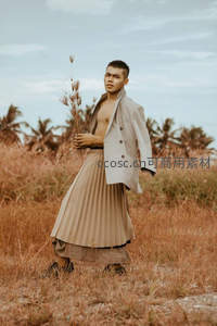 赤膊男子持干草立于旷野之中