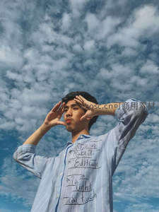 青年男子仰望蓝天双手遮阳摆造型
