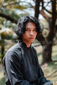 林间黑衣青年，卷发飘逸眼神深邃