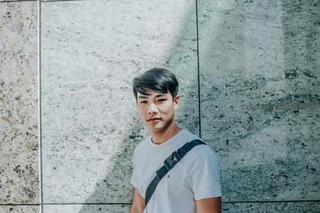 白衣青年倚靠大理石墙微笑