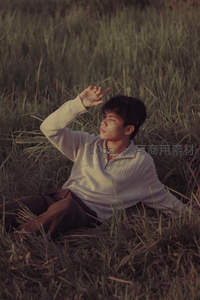 草地上沉思的青年男子