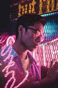 霓虹灯下戴眼镜的青年侧影