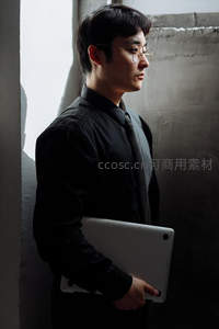 西装青年持电脑，侧影映窗光