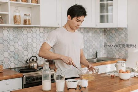 厨房中专注搅拌面糊的年轻男子