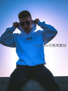 蓝光下的潮流青年，戴墨镜调整帽衫