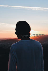 剪影少年凝望日落城市天际线