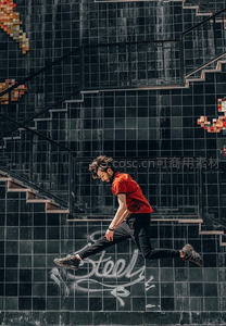 红衣青年在涂鸦楼梯间腾空跃起