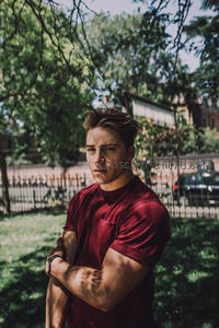 公园绿荫下穿红衣的健硕男子