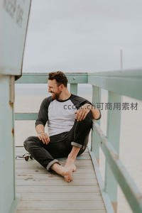 海滩救生塔下微笑放松的青年男子