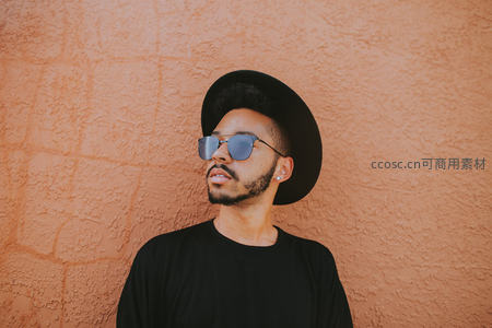 戴帽墨镜男倚墙沉思