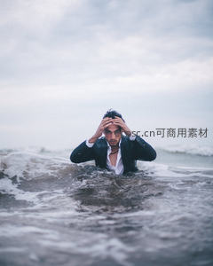 西装男海浪中抱头