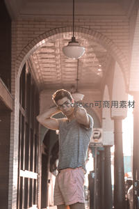 拱廊光影中，年轻男子自信摆姿