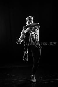 黑背景下的肌肉男格斗踢腿特写