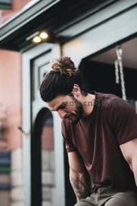 低头沉静的纹身男青年特写