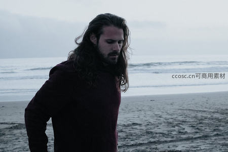 海边沉思的长发男子背影