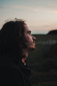 田野暮色中沉思的侧脸青年