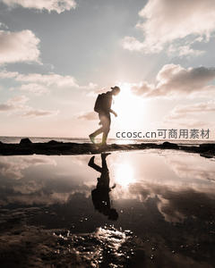 夕阳下海边行者剪影倒影