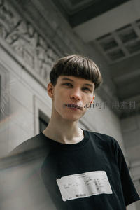 建筑廊柱下的少年，眼神深邃而专注