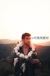 山巅花环男子凝望日落余晖
