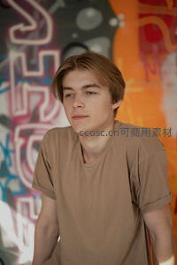 涂鸦墙前棕发少年沉思