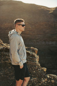 男子立于荒野山崖边沐浴金色夕阳余晖
