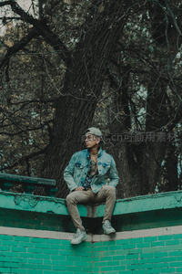 牛仔外套青年树下墙头沉思