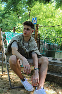 绿荫下坐在折叠椅上的帅气少年